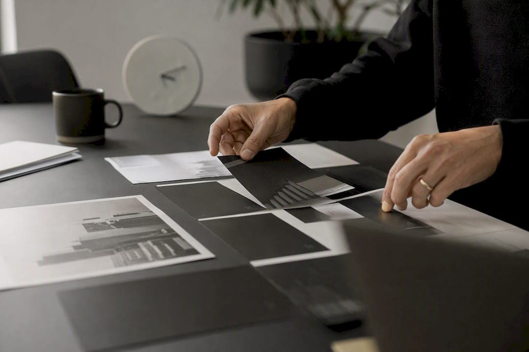 Hands arranging marketing asset mockups on desk