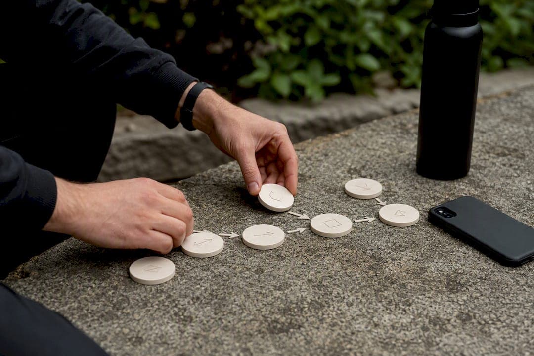 Hands arranging workflow tokens on black desk